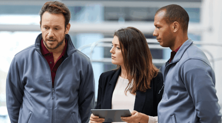 Femme utilisant une tablette pour guider l'équipe Gemba Walk, favorisant la collaboration en première ligne et la visibilité opérationnelle.